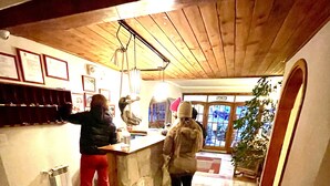 Un pasillo estrecho con techo de madera y pared de piedra. Hay un mostrador y una persona detrás.