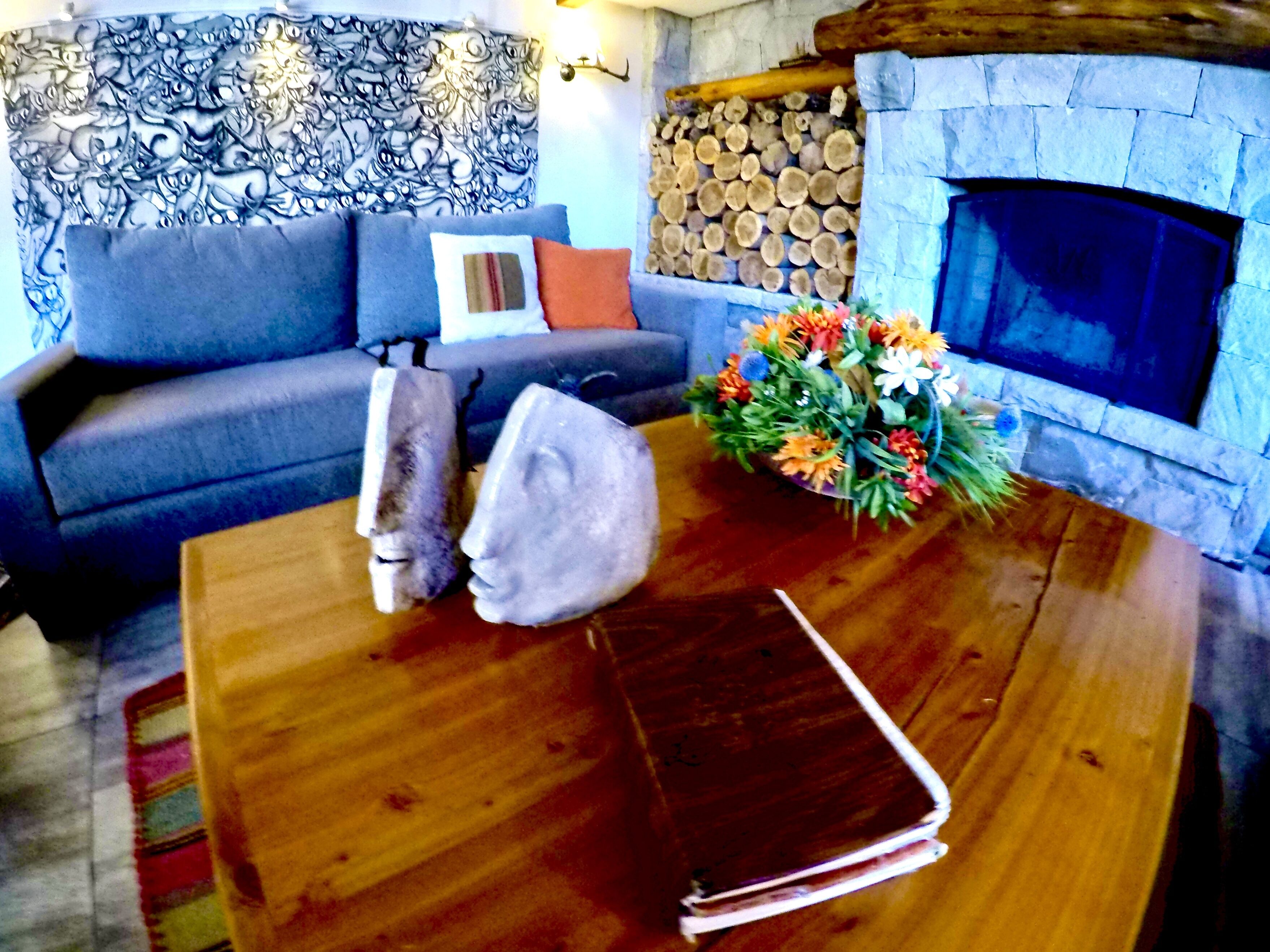 A living room with a sofa, a coffee table, a fireplace, and a decorative wall piece.