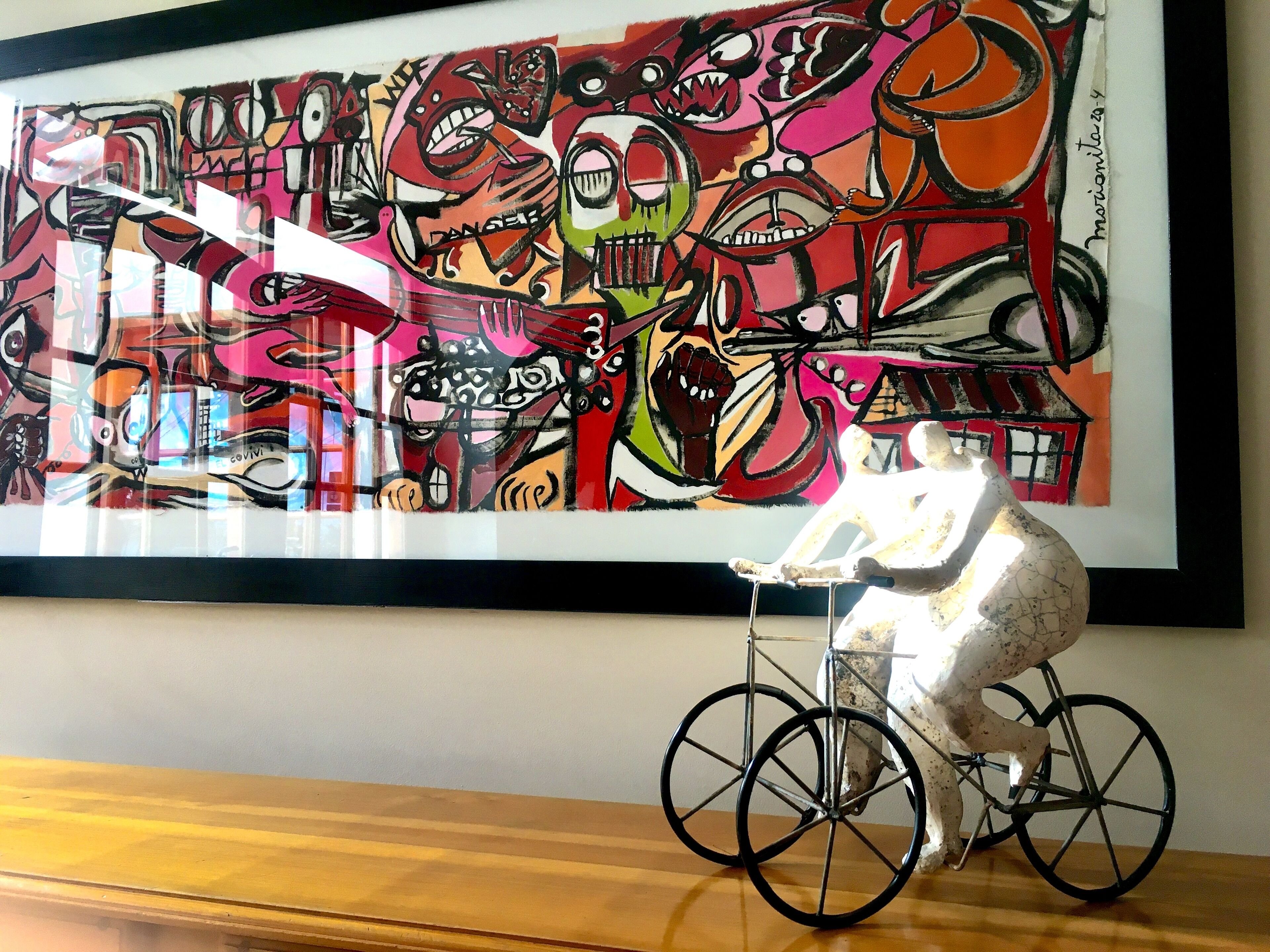 Een lijst met een abstract schilderij en een beeld van een paard op een fiets.