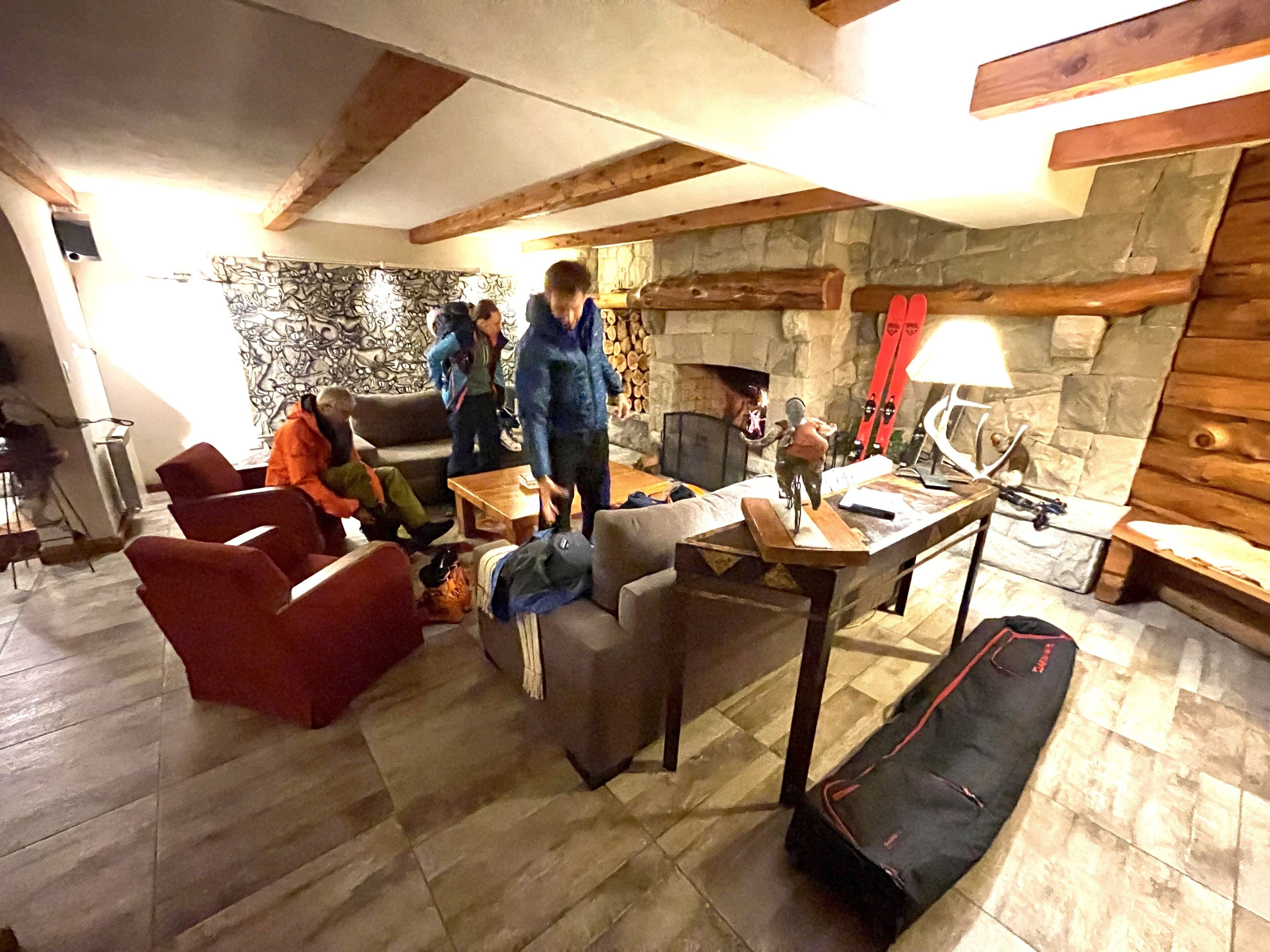 Una sala de estar acogedora con chimenea de piedra, vigas de madera y un soporte para esquíes.