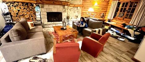 Una sala de estar acogedora con chimenea de piedra, vigas de madera y un área de descanso confortable.