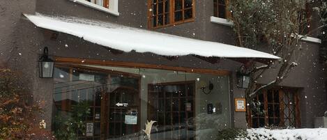 A two-story building with a covered entrance and snow-covered ground.