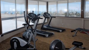 Un gimnasio con cintas de correr, una elíptica y una banca para pesas.