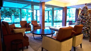 Un vestíbulo con muebles modernos, un árbol de Navidad y grandes ventanales que ofrecen vistas al exterior.