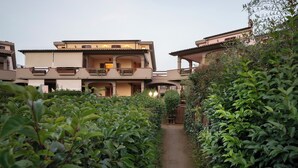 Uma trilha leva a um edifício com várias varandas e um portão.