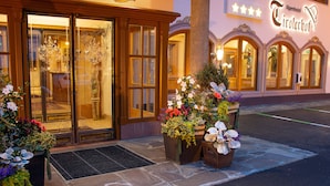 Het uiterlijk van het Alpenhotel met een traditionele gevel, grote ramen en een verzorgd entreegebied met bloemstukken.