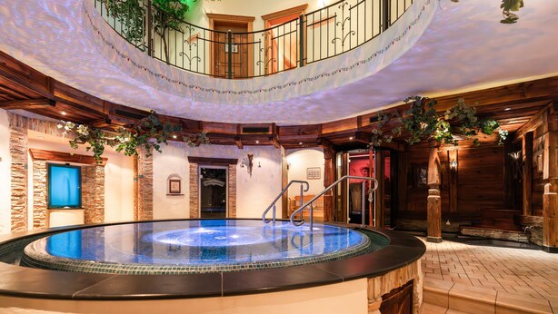 Een hottub in een houten interieur met een trap en een balkon.