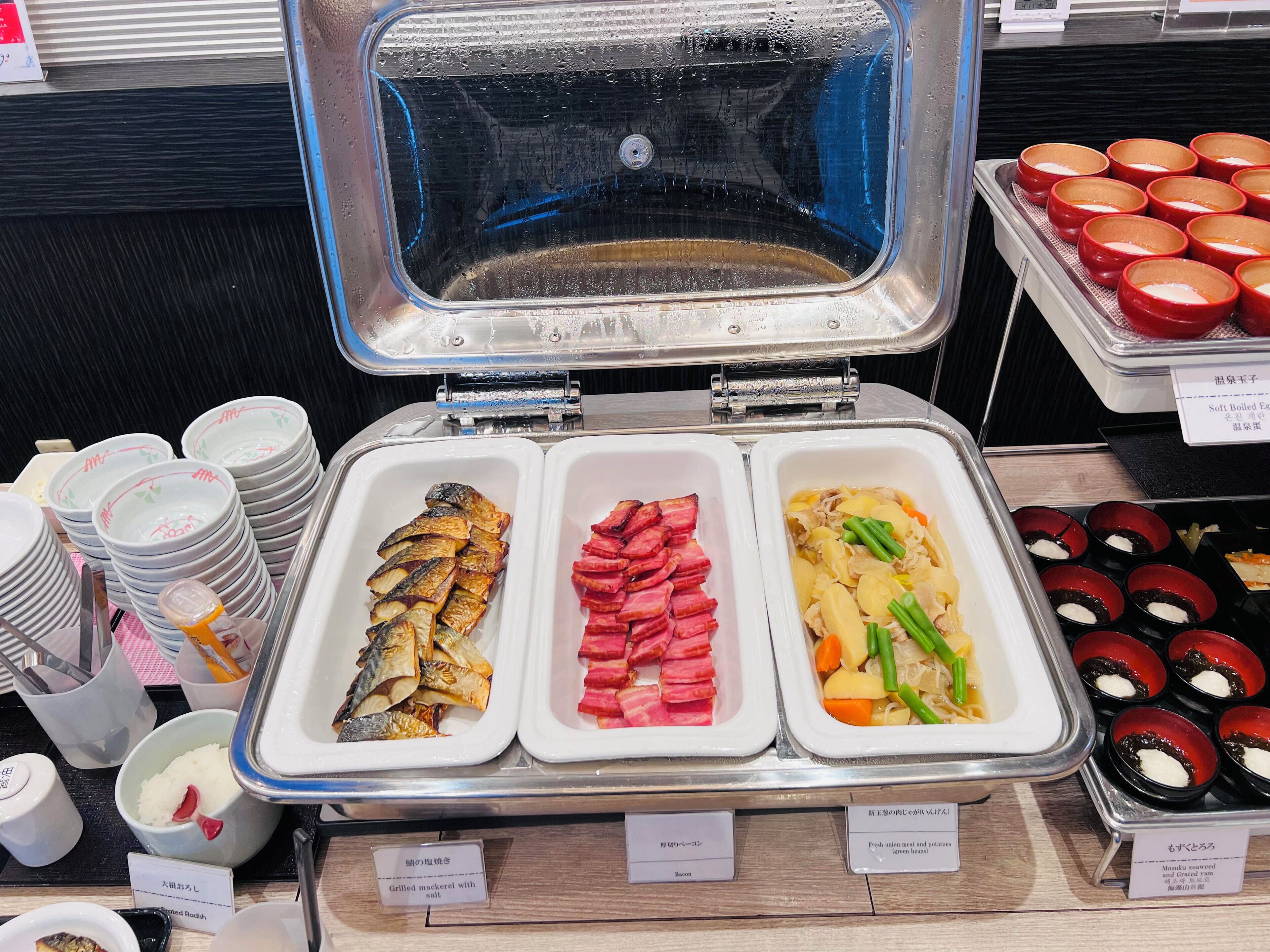 A buffet with grilled mackerel, bacon, and fresh onion meat and potatoes.