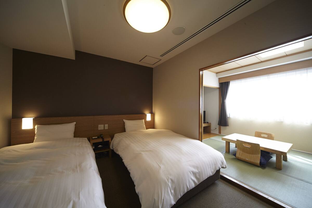 A hotel room with two beds, a desk, and a large mirror.