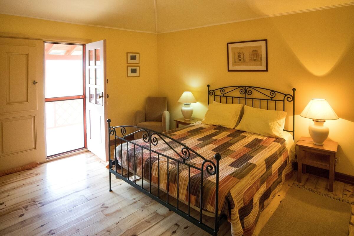 Une chambre à coucher avec un lit, deux lampes de chevet, une porte et un tableau encadré au mur.