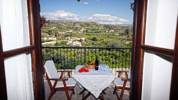 A balcony with a table set for two, overlooking a scenic landscape.