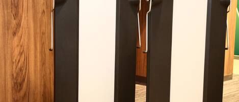 A set of three black and white lockers with handles and wheels, mounted on a carpeted floor.