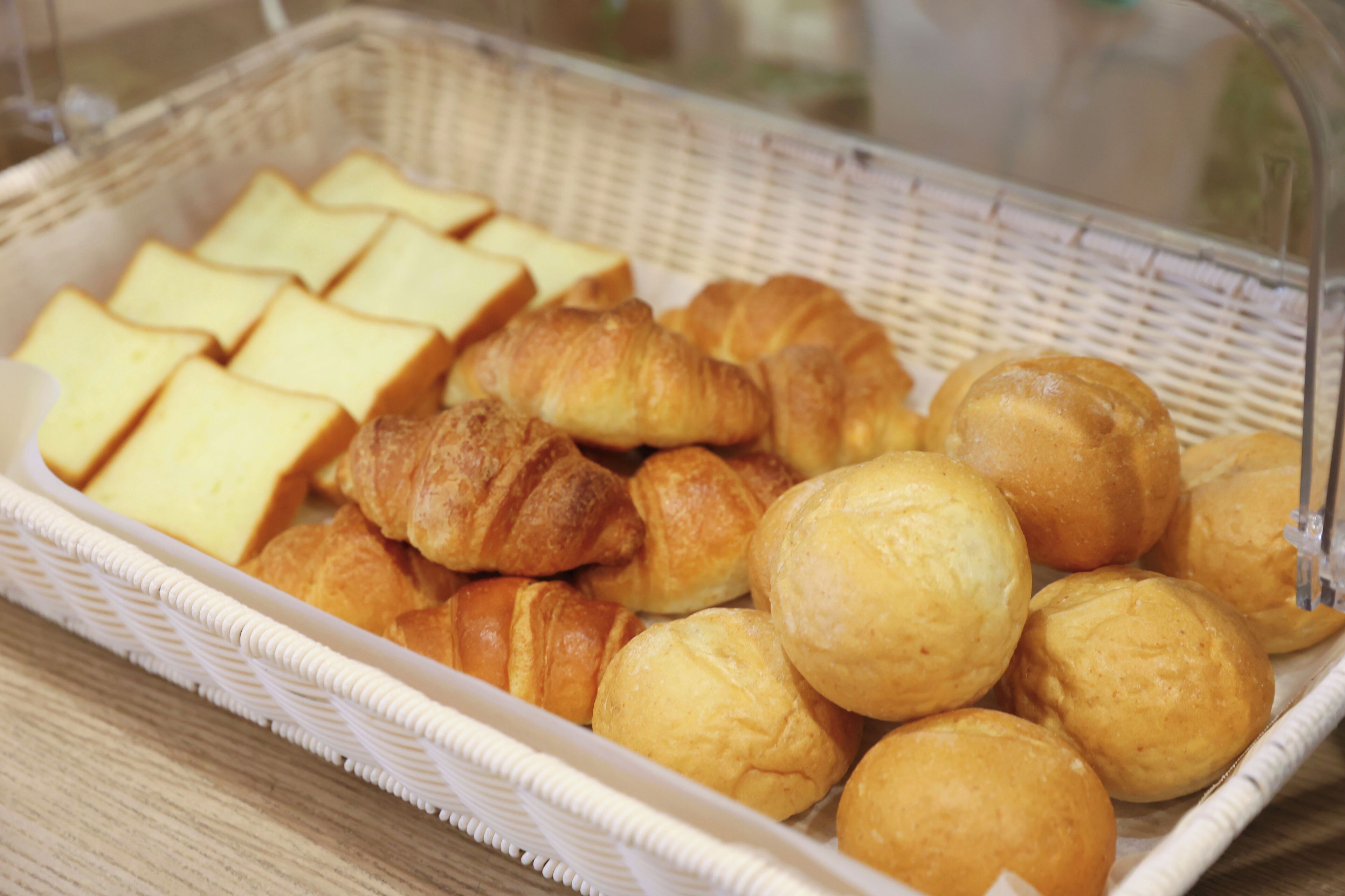 A basket containing various baked goods including croissants and bread slices.