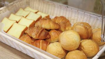 A basket containing various baked goods including croissants and bread slices.