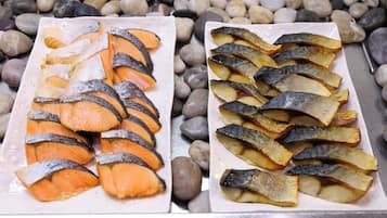 Two plates of sliced fish and potatoes on a table with a pebbled surface.