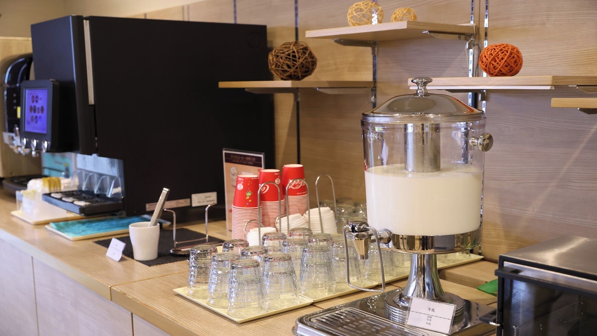 Una estación de café con cafetera, tazas y dispensador de leche.