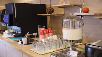 Una estación de café con cafetera, tazas y dispensador de leche.