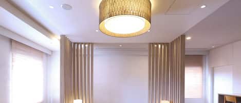 Una habitación moderna y bien iluminada, con una zona de estar central, suelos de madera y una lámpara de techo circular grande.