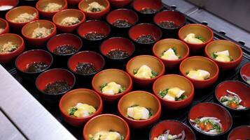 Una variedad de recipientes pequeños rojos con diferentes alimentos, dispuestos en una bandeja.
