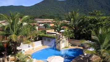 Una piscina al aire libre, sombrillas, sillones reclinables de piscina