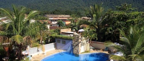 Una piscina al aire libre, sombrillas, sillones reclinables de piscina