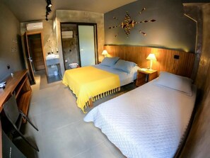 Habitación de hotel con dos camas, cabecero de madera, una obra de arte colgada en la pared y un escritorio con silla.