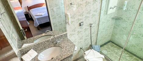 A bathroom with a marble-tiled floor, a glass-enclosed shower, a sink with a mirror, and a toilet.