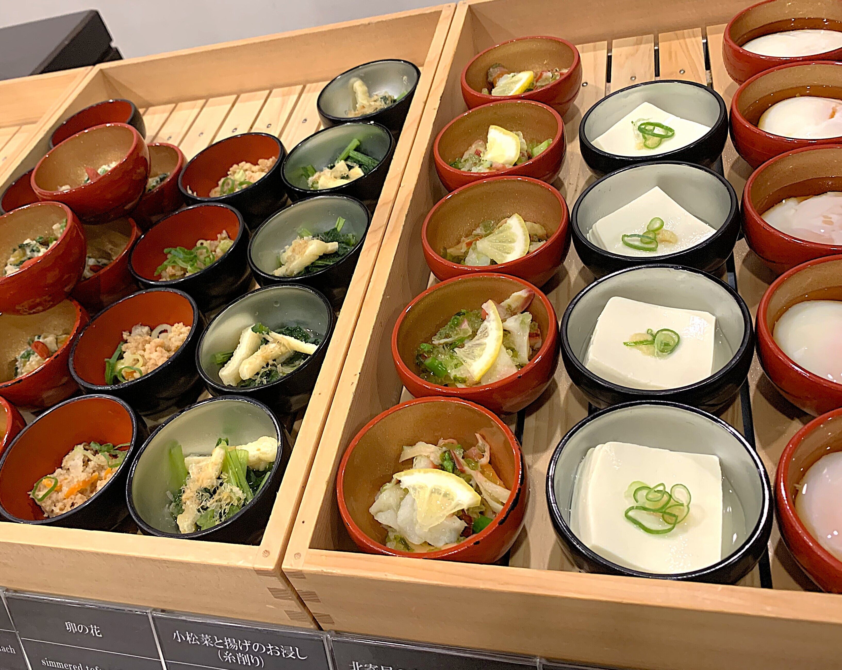 A variety of dishes in small bowls, arranged in wooden boxes.