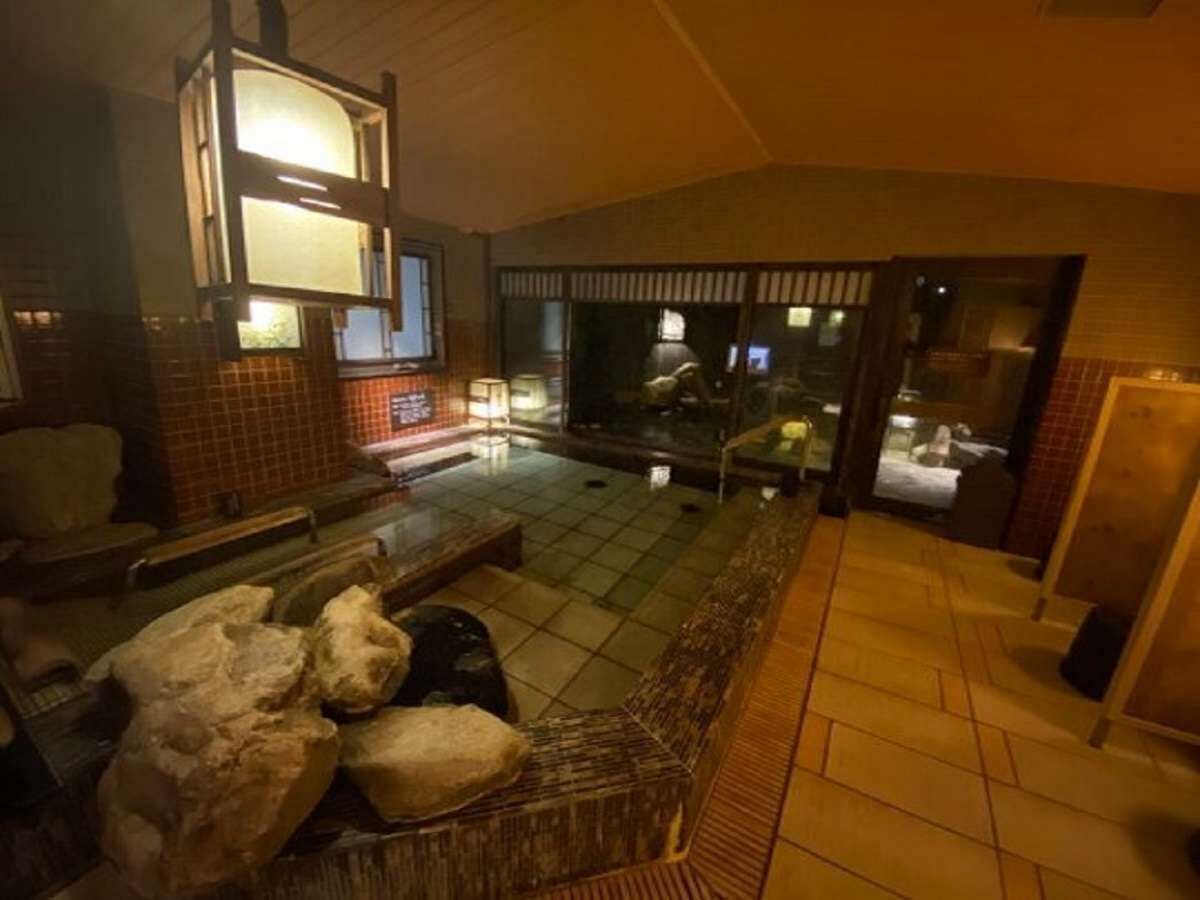 A spacious indoor area with a seating arrangement, a large window, and a tiled floor.