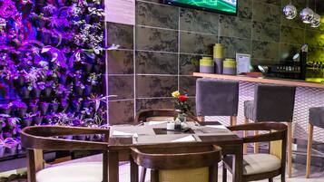 Un restaurante moderno con una pared de plantas en macetas, un televisor de pantalla plana y una zona de bar.