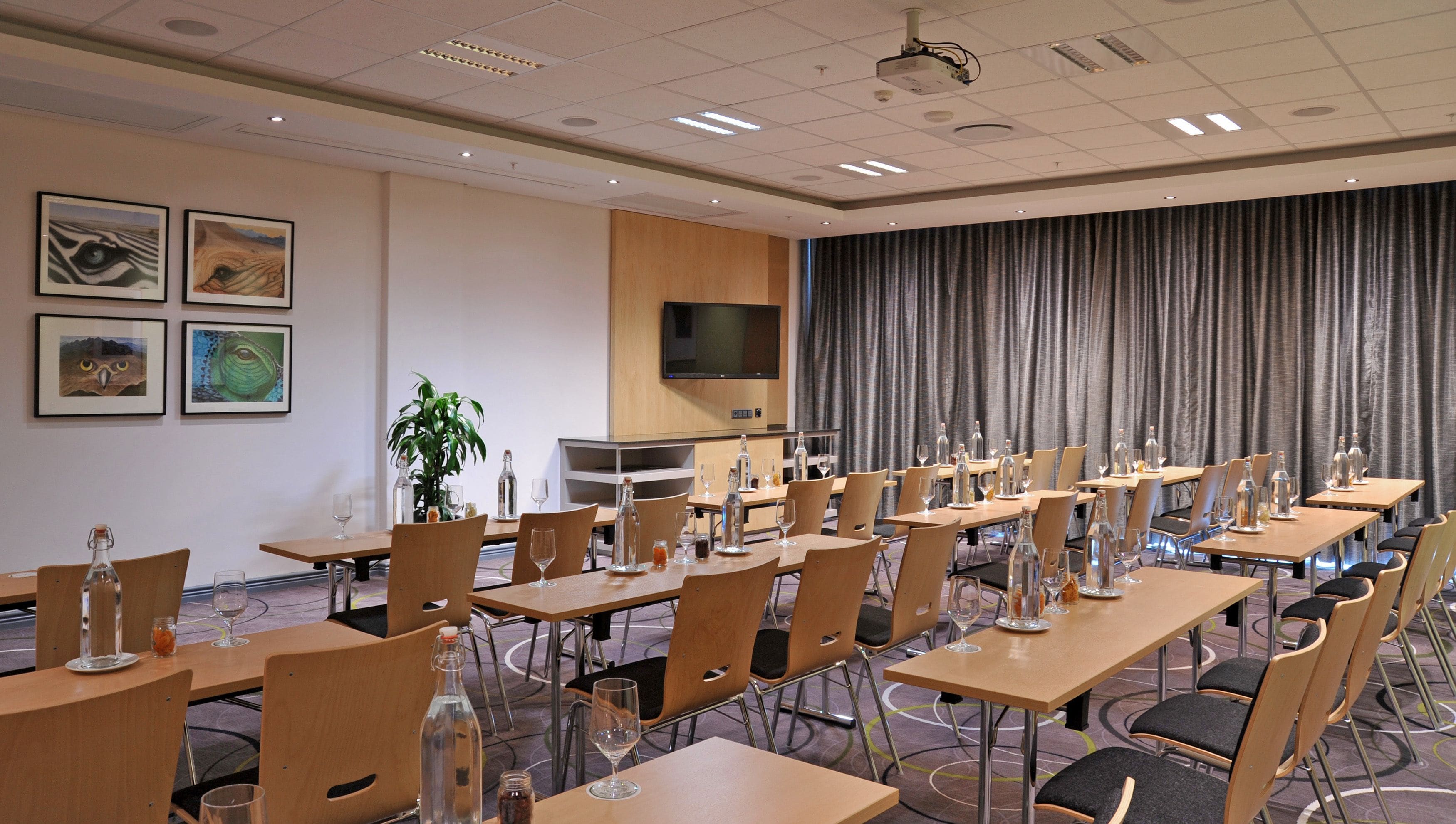 A conference room with multiple tables, chairs, a television, and artwork on the walls.