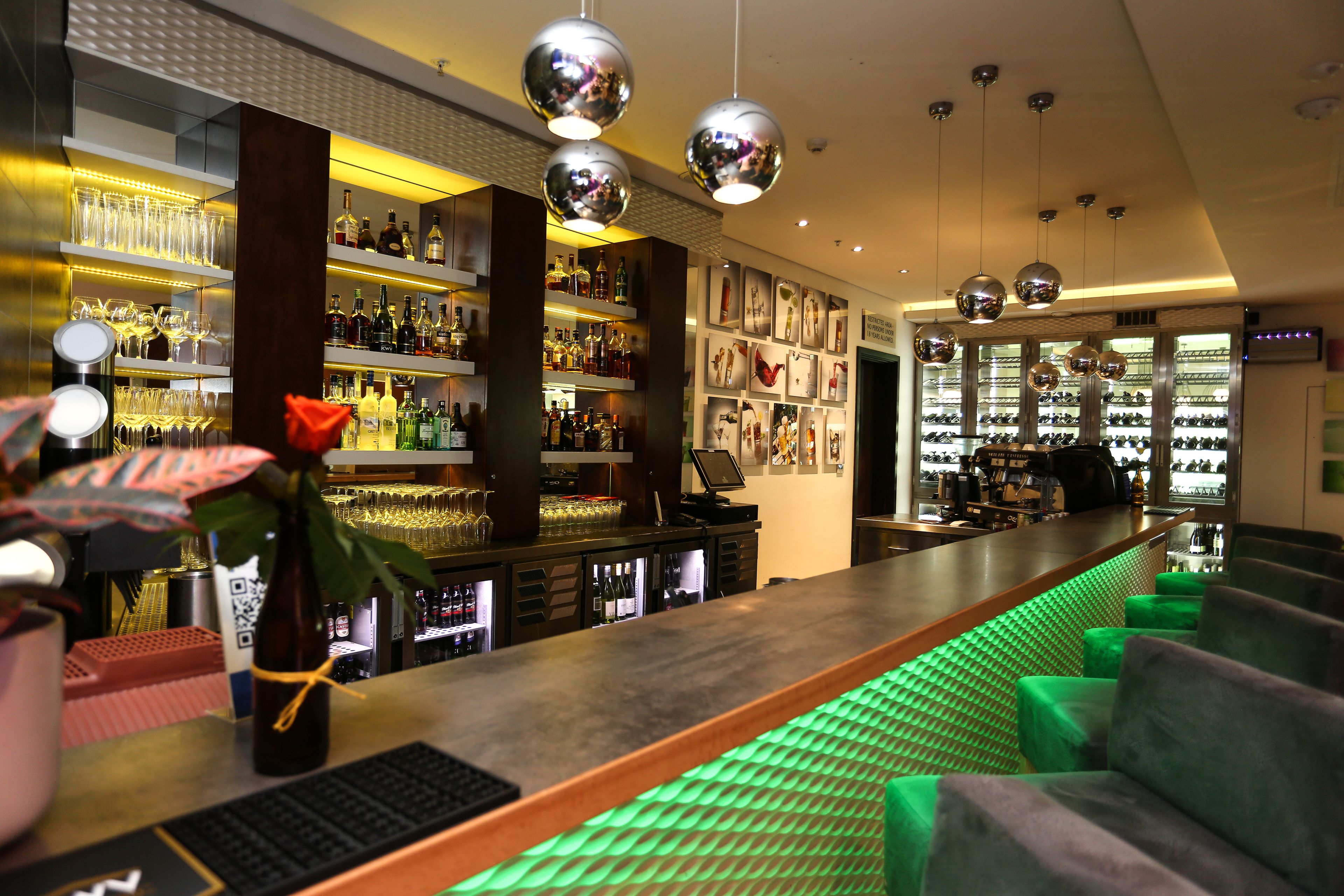 A bar area with shelves of bottles, glasses, and a bar counter.