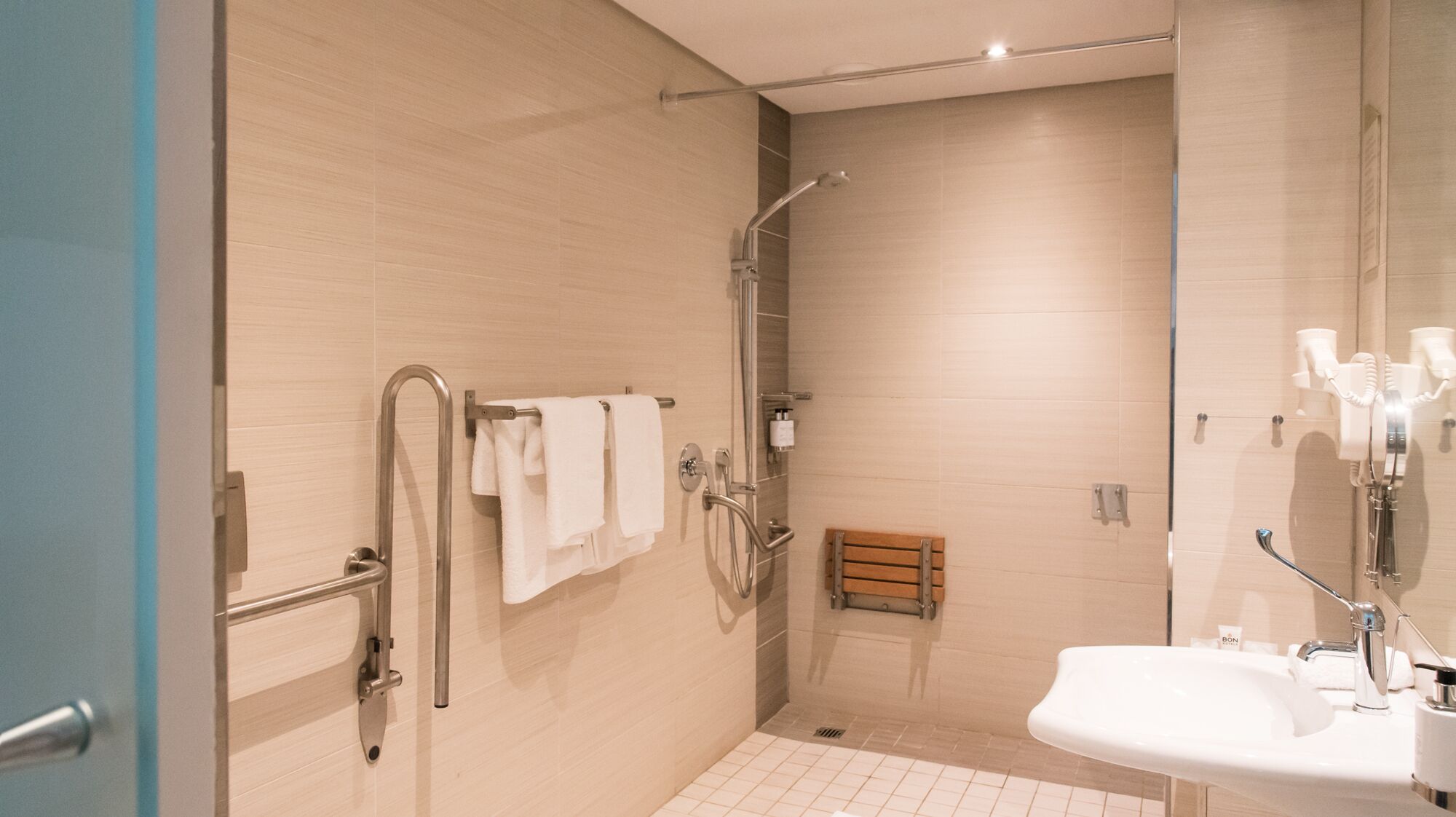 Ein modernes Badezimmer mit Dusche, Waschbecken und Handlauf.
