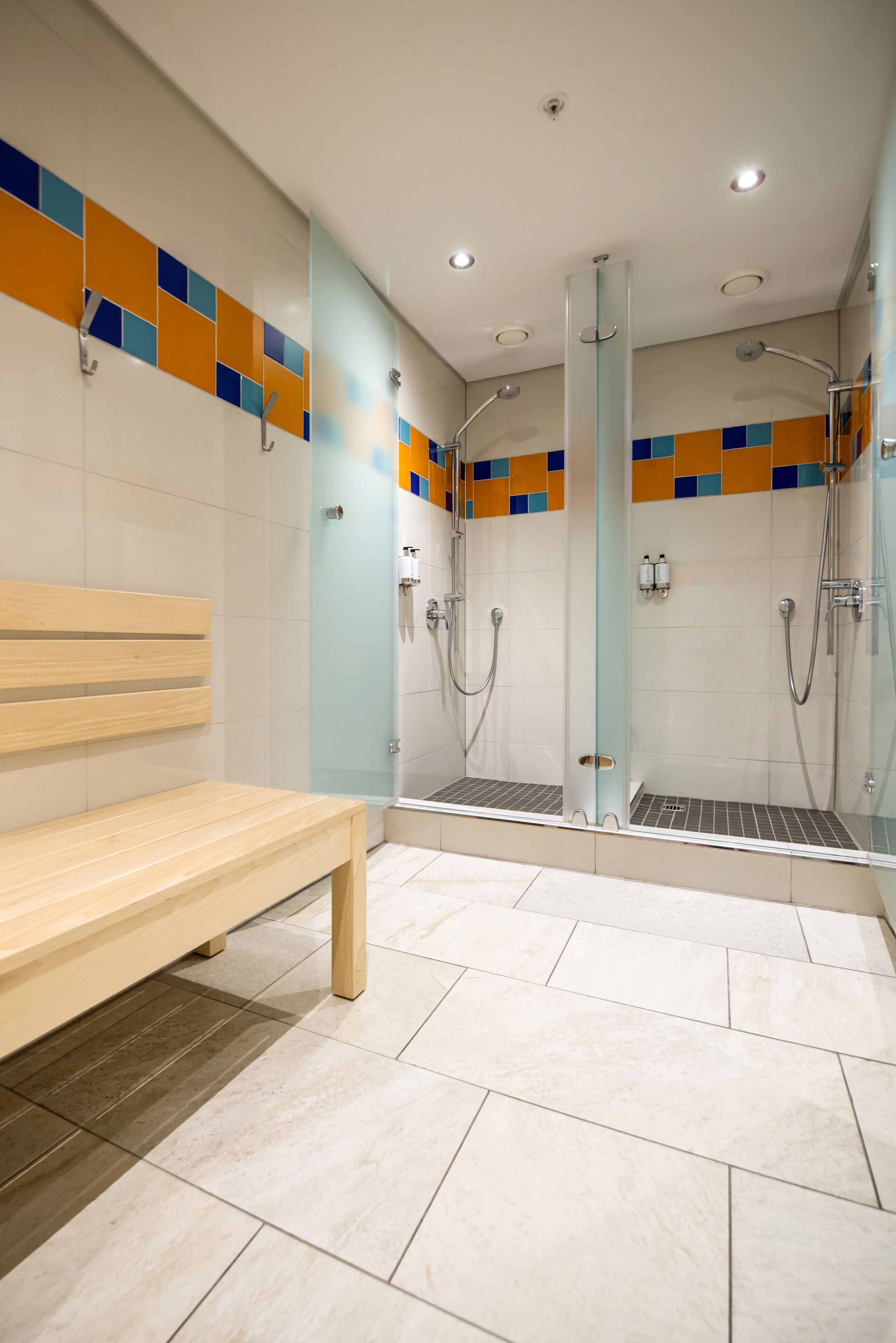 A modern bathroom with a bench, a glass shower enclosure, and tiled walls.