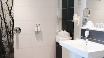 Un baño moderno con ducha a ras de suelo, un espejo grande y un lavabo blanco.