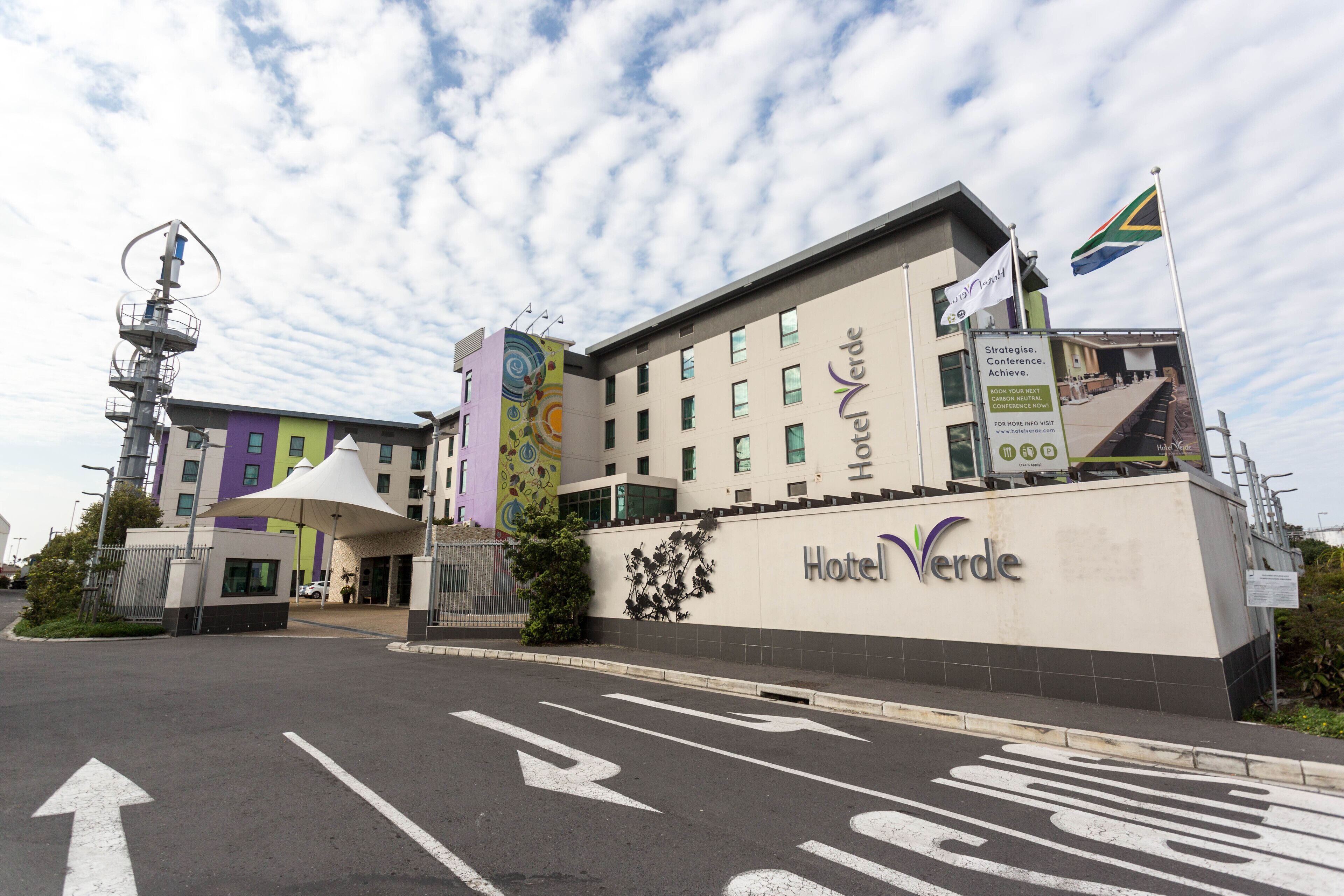 Un hotel con fachada moderna, una entrada destacada y una bandera.