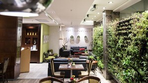 A modern interior with a dining area, a reception desk, and a vertical garden wall.