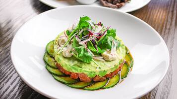 A plate of food with avocado, tomato, and cucumber slices, garnished with herbs.