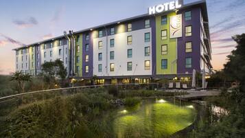 Un hotel de varios pisos con un letrero que dice "HOTEL Verde" y un reflejo en una fuente.