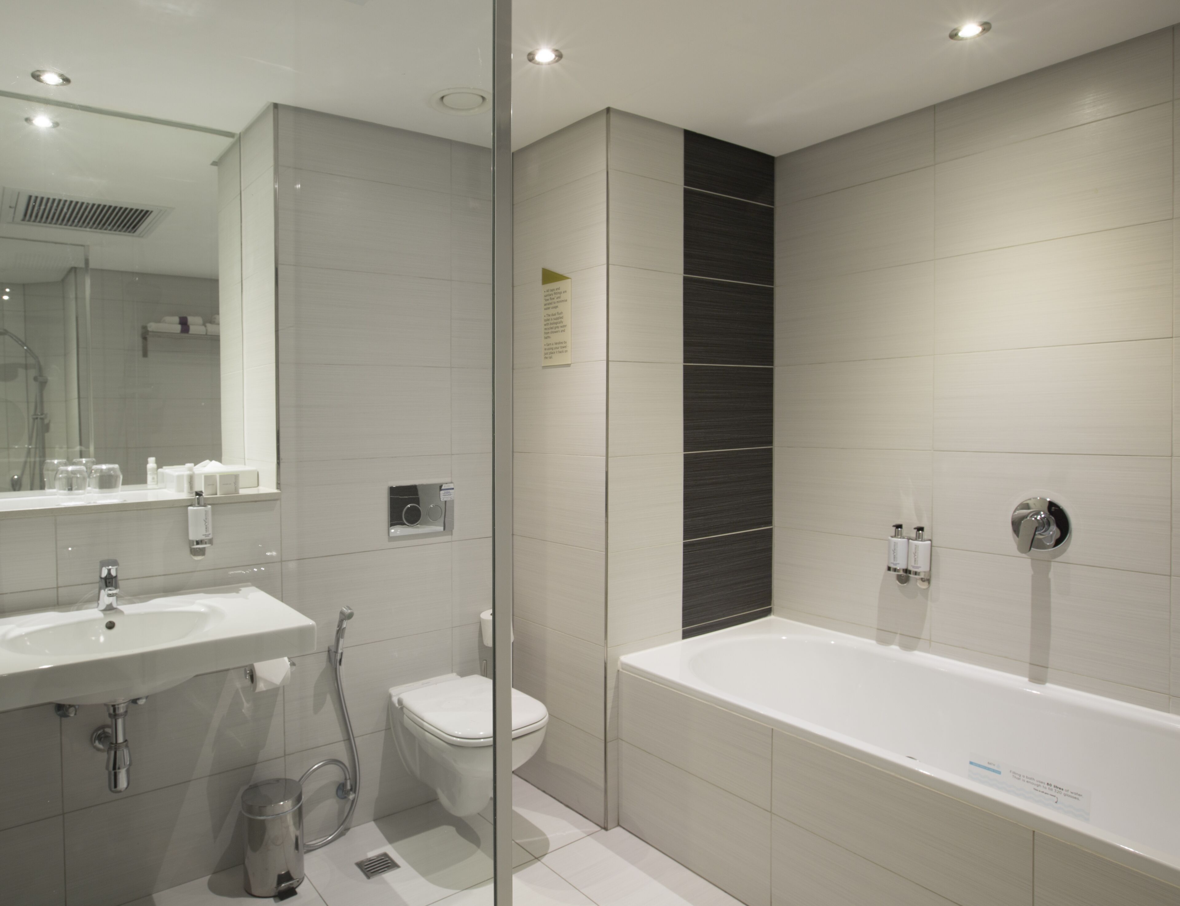A modern bathroom with a large bathtub, a separate toilet, and a vanity with a mirror.