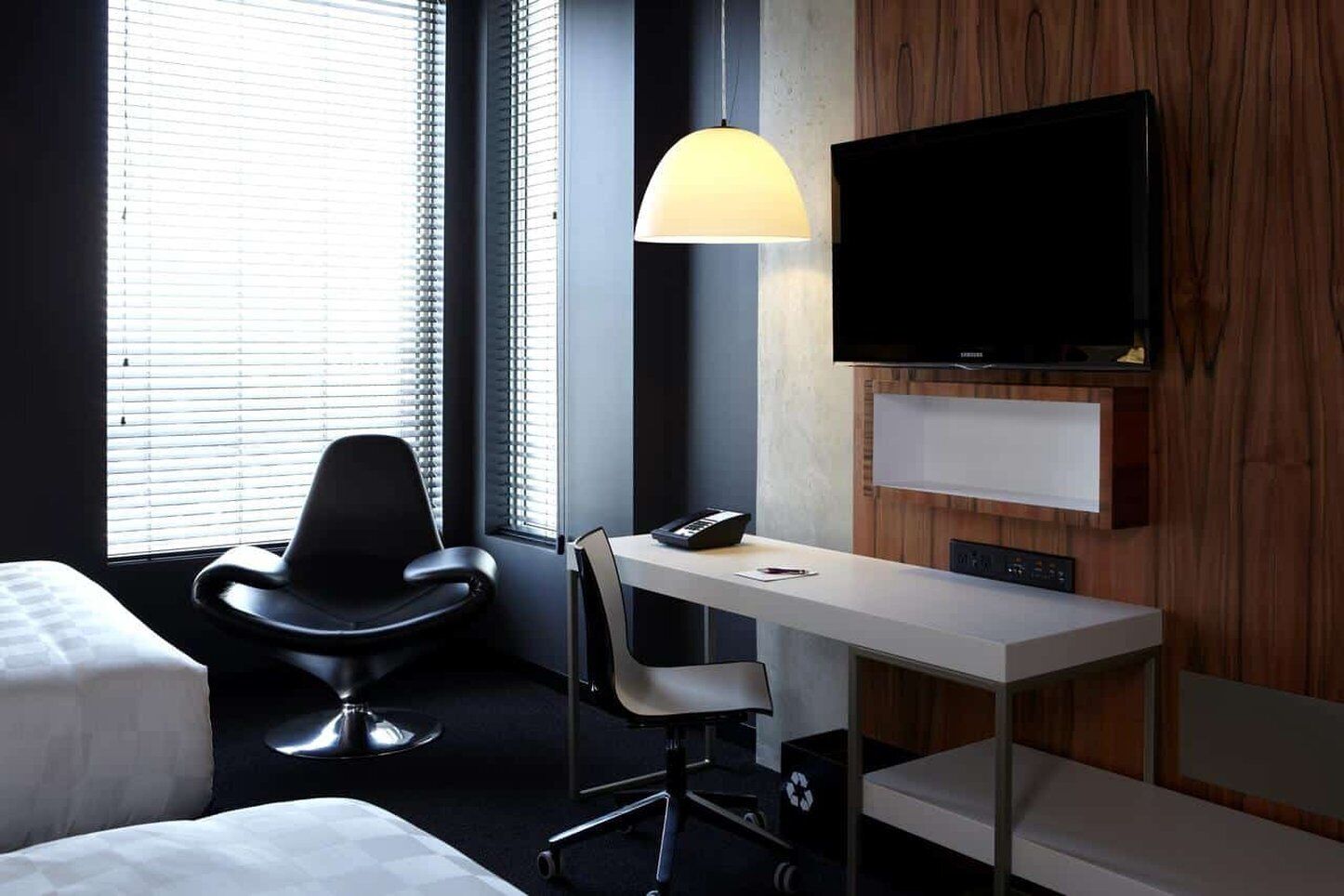 Una habitación de hotel moderna con escritorio, silla y televisor montado en la pared.