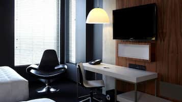 Una habitación de hotel moderna con escritorio, silla y televisor montado en la pared.