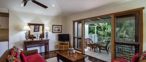 A spacious living area with a ceiling fan, a television, and a dining table.