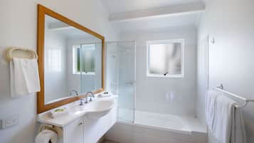 Une salle de bain moderne avec un grand miroir, deux lavabos, une douche et une baignoire.