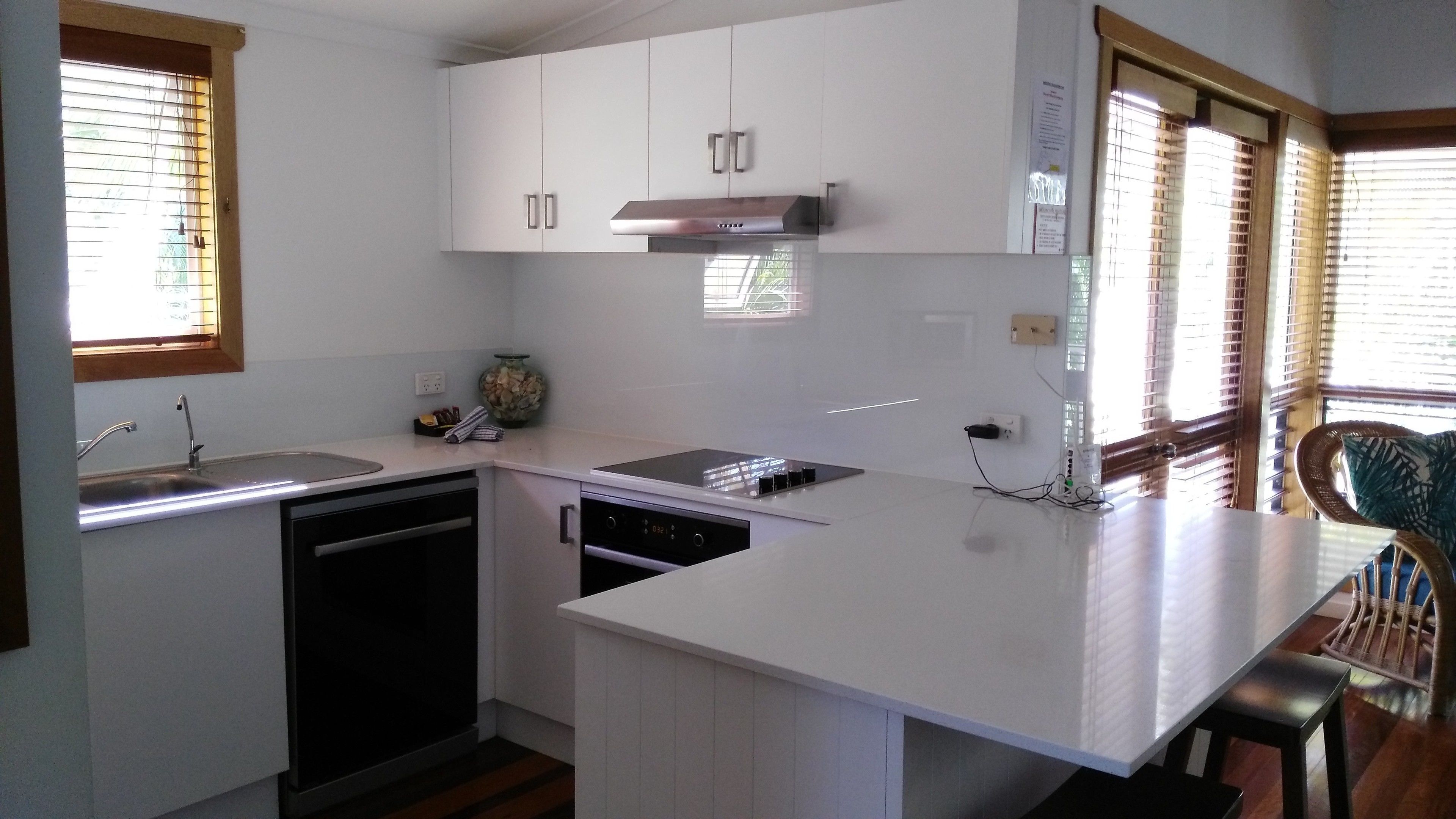 A compact kitchen with white cabinetry, a built-in dishwasher, and a stove.