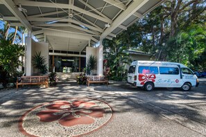 A covered entrance with a white van parked nearby, benches, and a decorative pavement design. - South Pacific Resort & Spa Noosa (Noosaville)