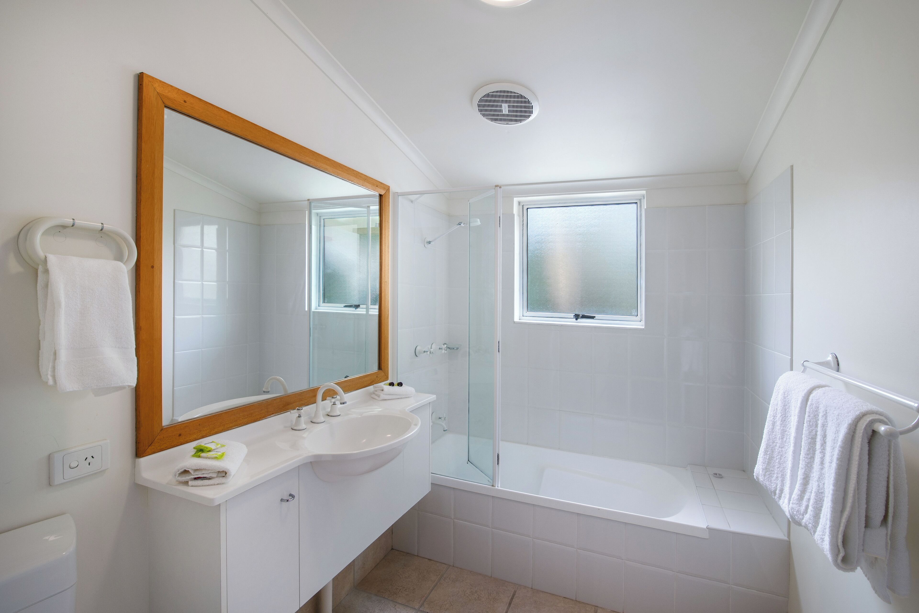 A modern bathroom with a large mirror, white sink, and a glass-enclosed shower area.
