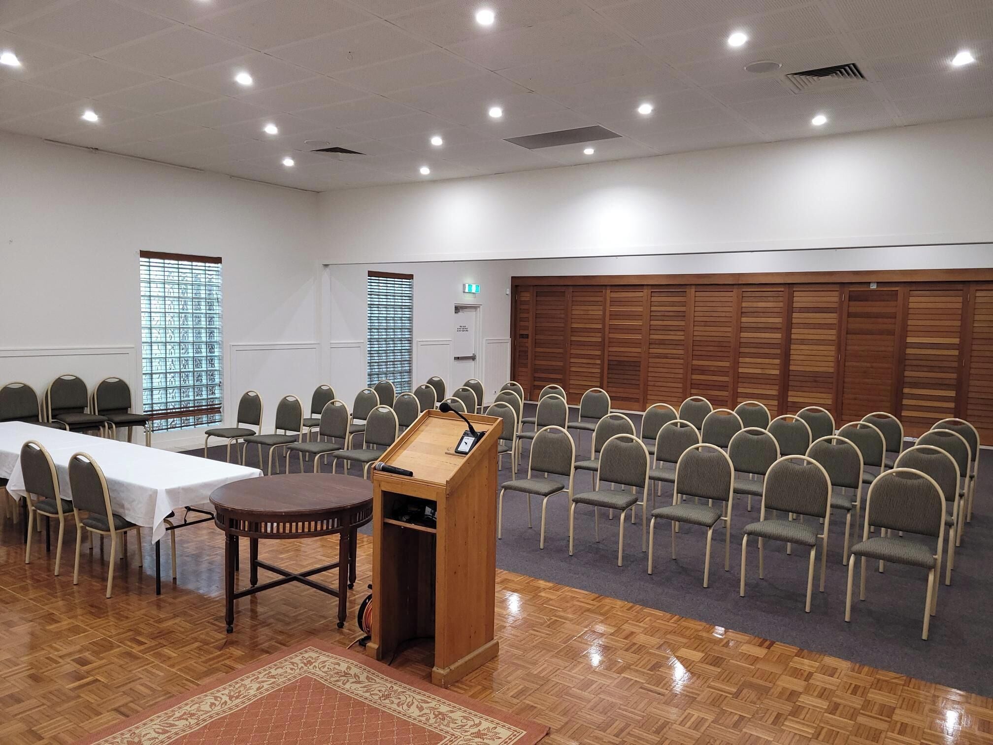 A conference room with a podium, rows of chairs, a table, and a patterned carpet.