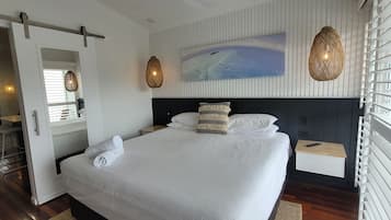 Una habitación de hotel moderna con una cama grande, un cuadro en la pared y vista al mar.