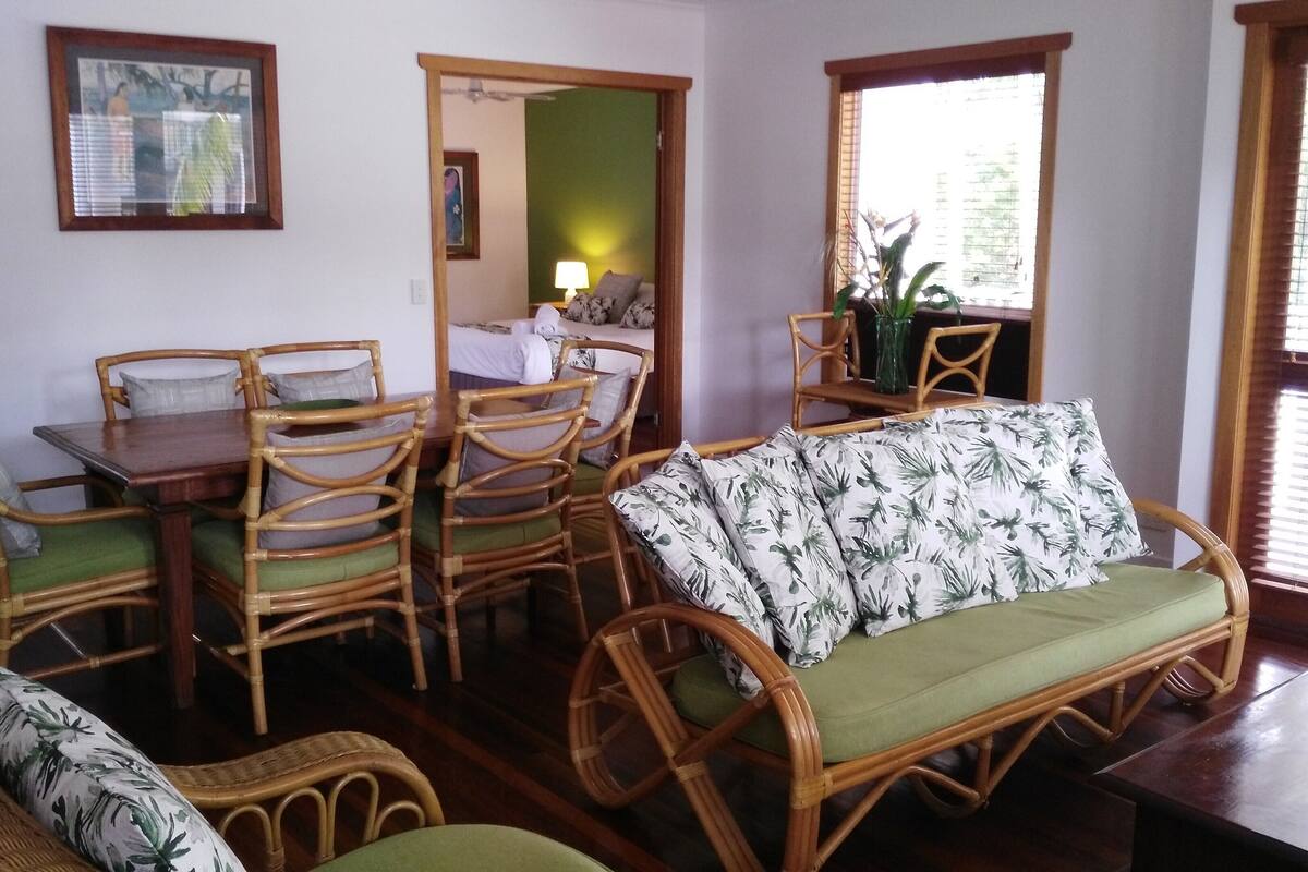 Una habitación con una mesa de comedor y sillas, un sofá y una ventana con persianas.